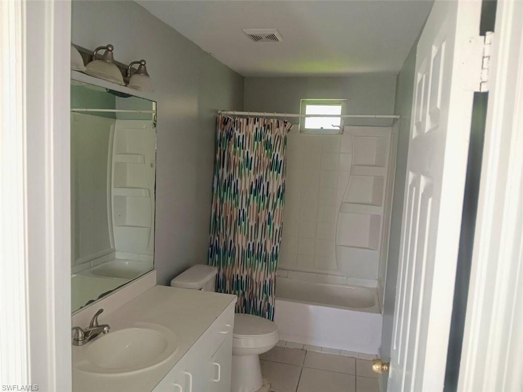 Full bathroom featuring light tile patterned flooring, vanity, and shower / tub combo with curtain