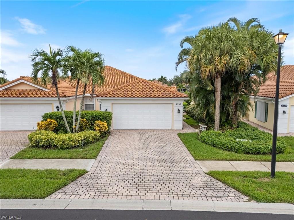 Mediterranean / spanish-style house with stucco siding, driveway, a tile roof, and a garage