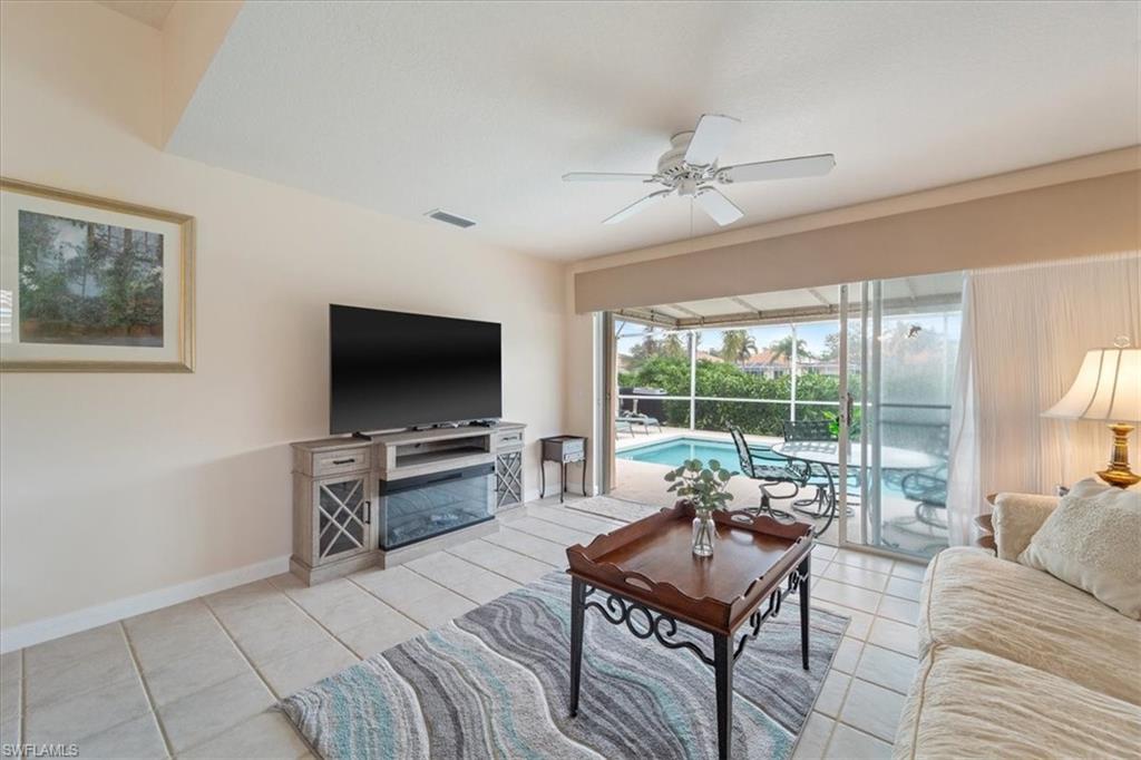 Living area with light tile patterned flooring, ceiling fan, and a sunroom