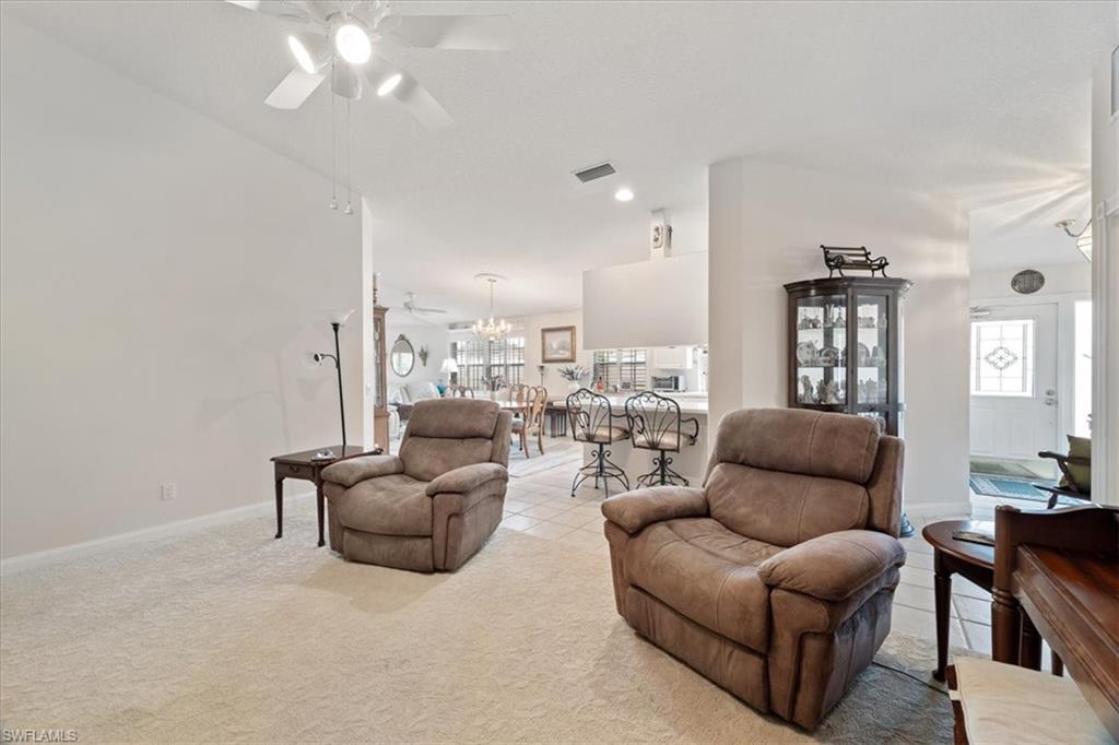 Living room with light carpet, ceiling fan, light tile patterned floors, and recessed lighting
