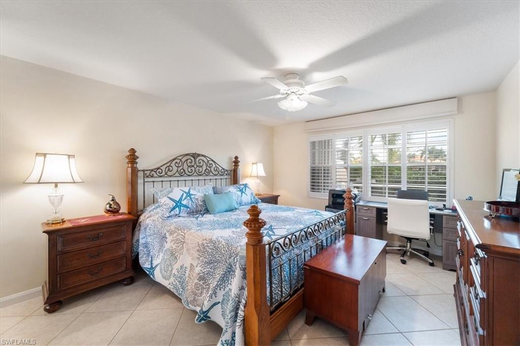 Bedroom with light tile patterned floors, ceiling fan, and a desk