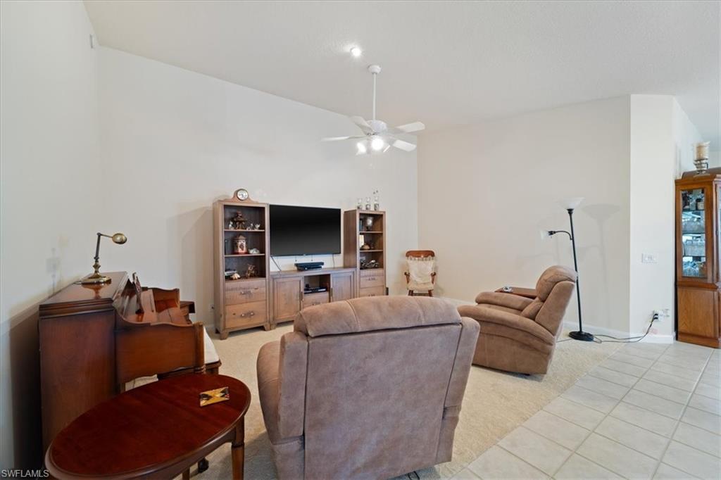 Living area featuring light tile patterned floors, ceiling fan, and light colored carpet