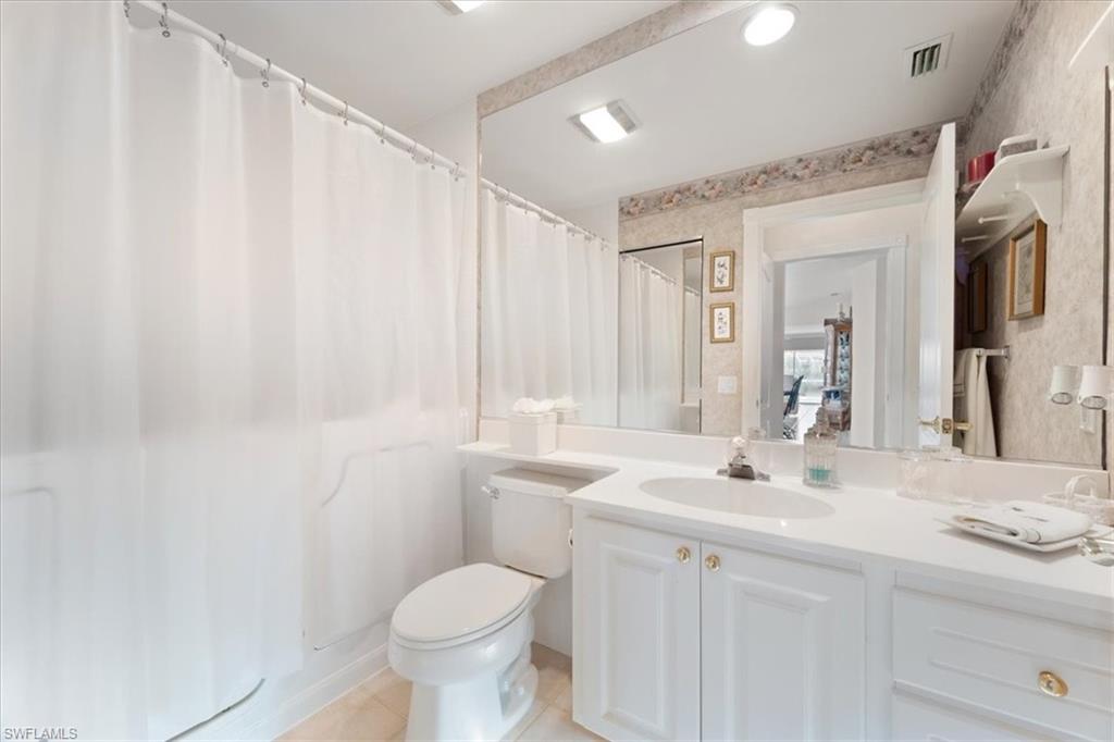 Bathroom featuring vanity, wallpapered walls, light tile patterned floors, and a shower with curtain