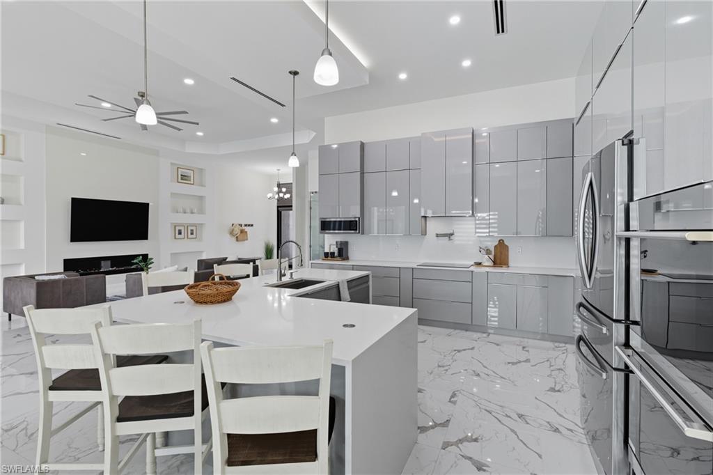 Kitchen featuring gray cabinets, a kitchen breakfast bar, open floor plan, pendant lighting, and a kitchen island with sink