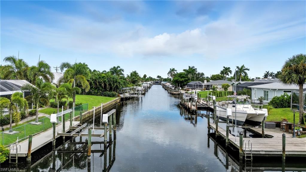 Dock area with room for a boat lift, a water view, a residential view, and a lawn