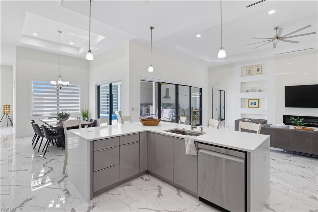 Kitchen featuring modern cabinets, open floor plan, light marble finish flooring, a raised ceiling, and gray cabinets