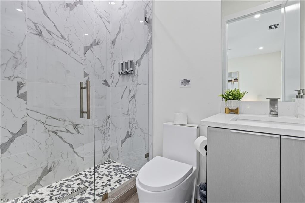 Bathroom with vanity and a marble finish shower