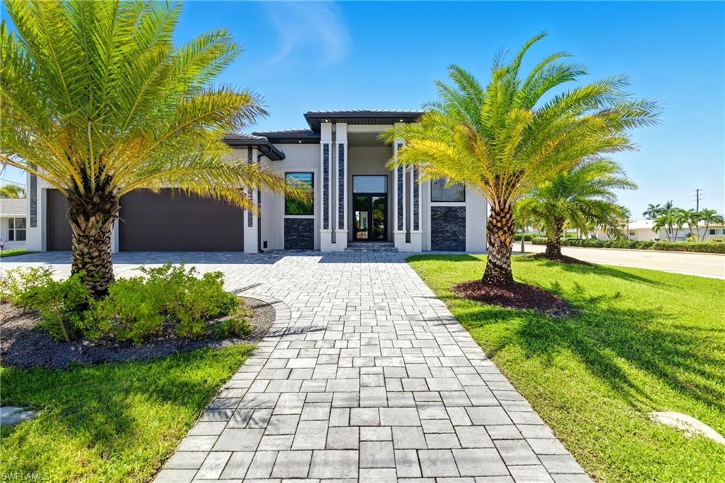 View of front of property with decorative driveway, stucco siding, a garage, a front lawn, and a tile roof