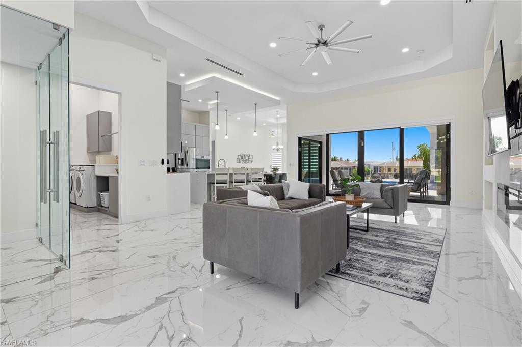 Living room with a raised ceiling, light marble finish floors, recessed lighting, washer / clothes dryer, and a high ceiling