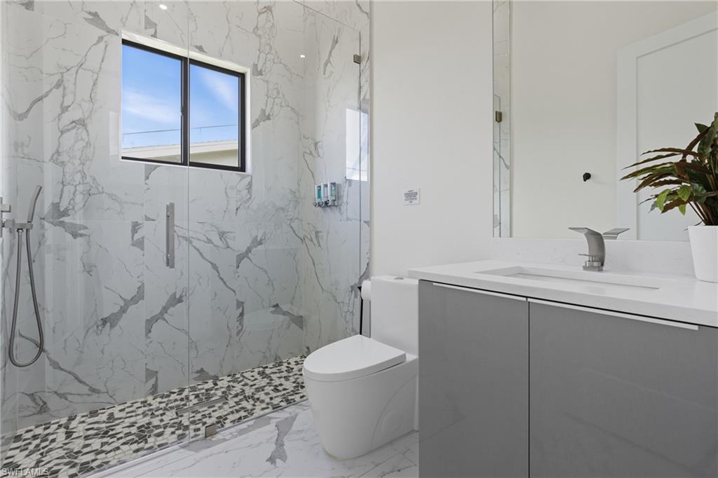 Full bathroom with vanity, light marble finish flooring, and a marble finish shower