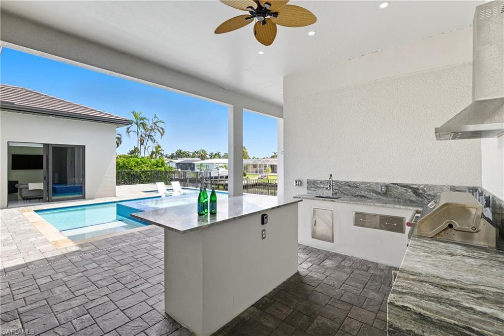 View of patio with area for grilling and a ceiling fan