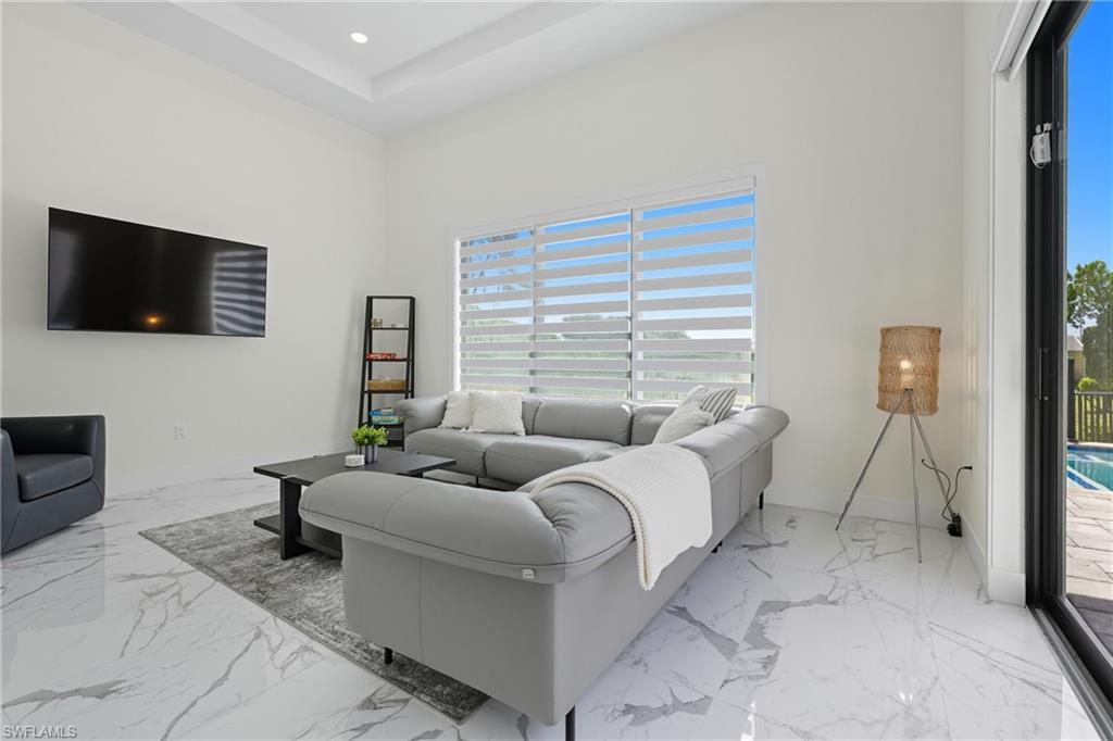 Living area featuring a tray ceiling, recessed lighting, and light marble finish floors