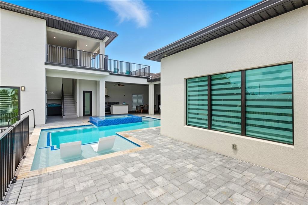 View of pool with ceiling fan, a patio, a pool with connected hot tub, and a balcony