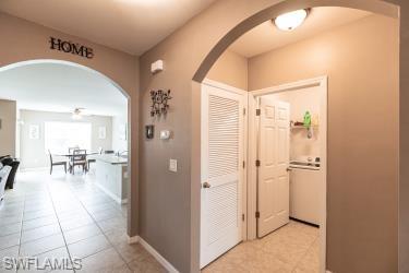 Hall featuring arched walkways and light tile patterned floors
