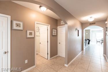 Corridor featuring arched walkways and light tile patterned floors