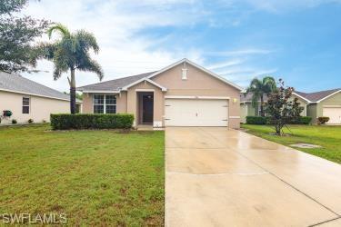 View of front of home with a front yard, driveway, stucco siding, and a garage