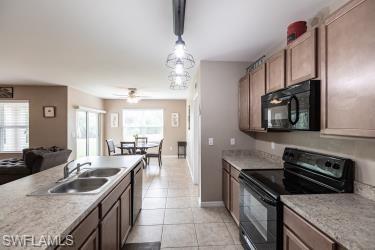 Kitchen with black appliances, light countertops, hanging light fixtures, light tile patterned flooring, and open floor plan