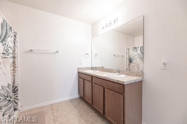 Full bathroom with double vanity, a shower with shower curtain, and light tile patterned floors