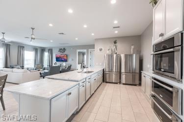 Kitchen featuring appliances with stainless steel finishes, white cabinetry, open floor plan, a warming drawer, and recessed lighting