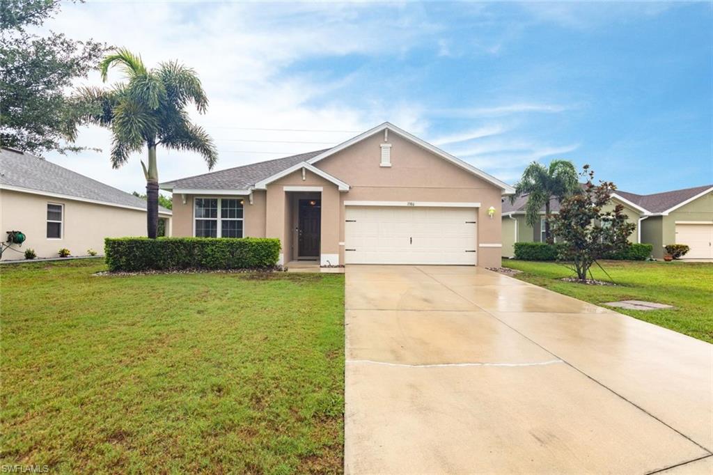 Ranch-style house featuring stucco siding, a front yard, driveway, and a garage