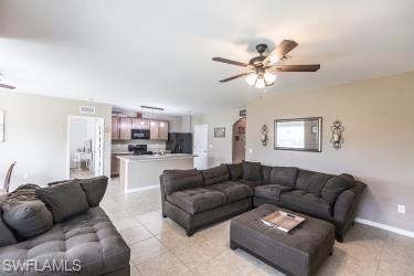 Living room featuring ceiling fan, light tile patterned floors, and arched walkways