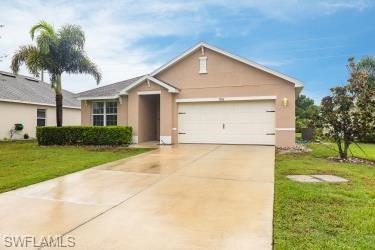 View of front facade with stucco siding, a front yard, driveway, and an attached garage