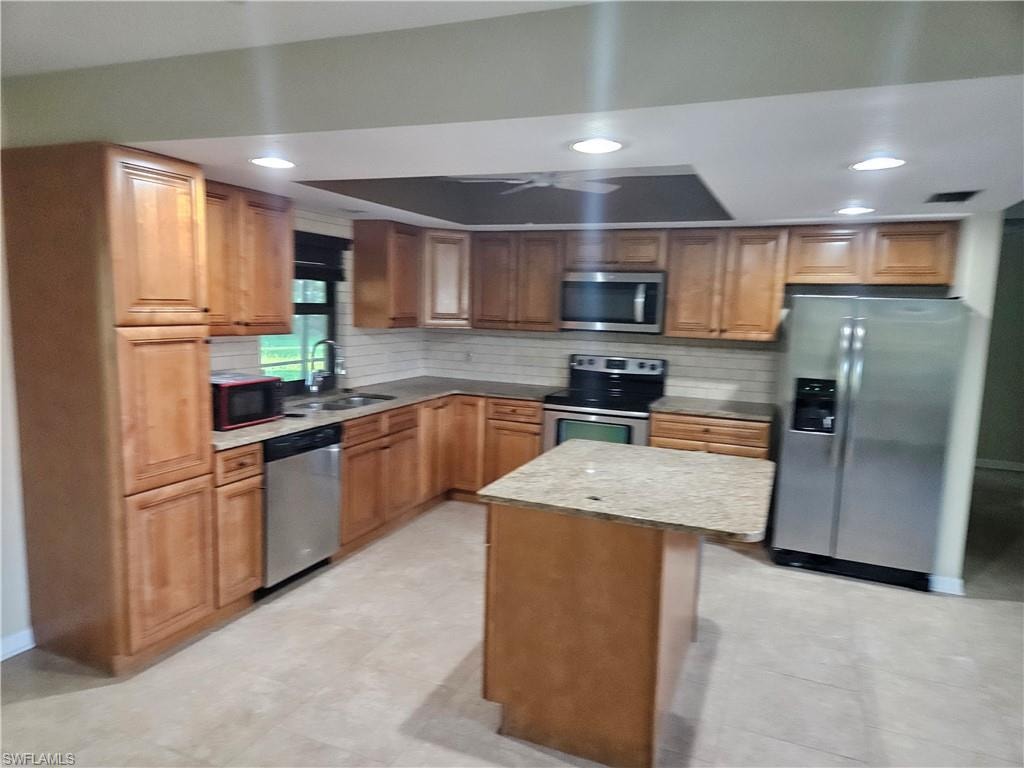 Kitchen featuring stainless steel appliances, tasteful backsplash, recessed lighting, a kitchen island, and brown cabinets