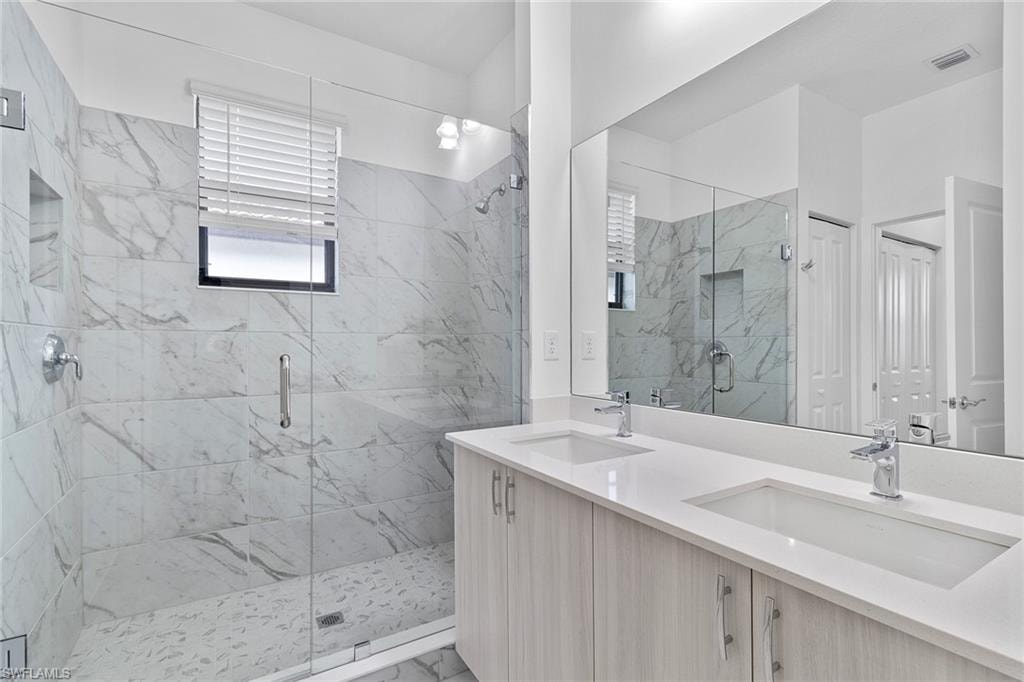 Primary bathroom with modern tile finish shower, and double vanity