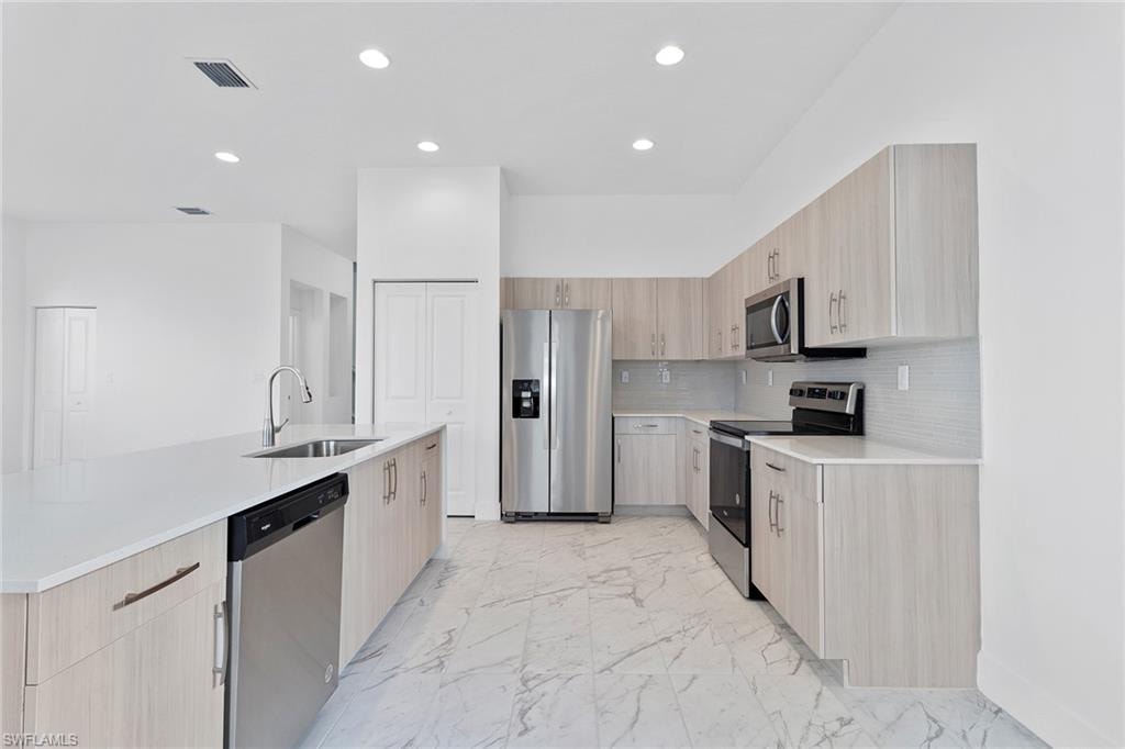 Kitchen with modern cabinets, stainless steel appliances, tasteful backsplash, and quartz countertops