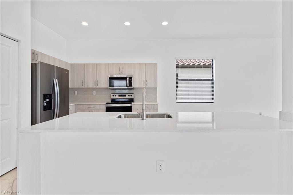 Kitchen with modern cabinets, stainless steel appliances, tasteful backsplash, and quartz countertops