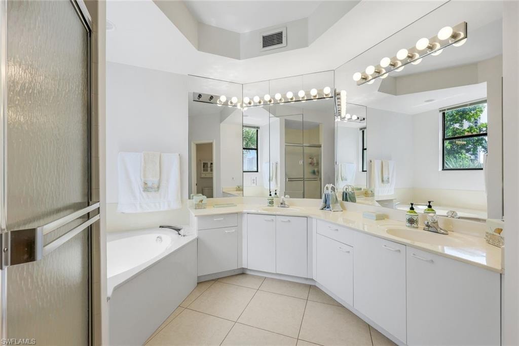 Bathroom with a shower stall, a bath, light tile patterned flooring, and double vanity