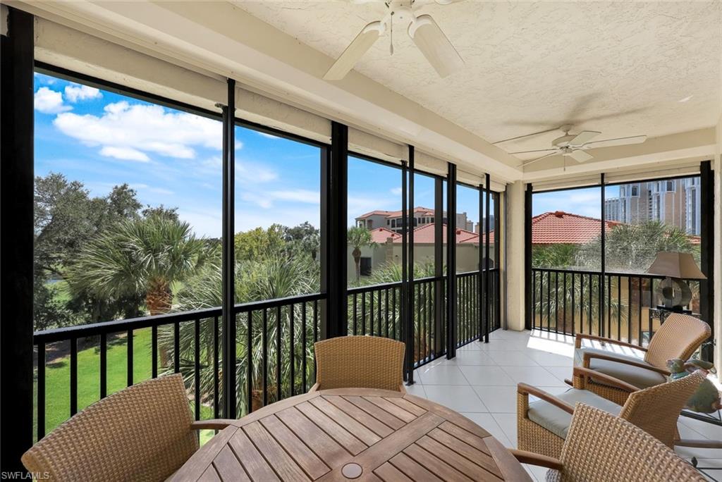 Sunroom / solarium featuring ceiling fan, a balcony, tile patterned flooring, expansive windows, and a textured ceiling