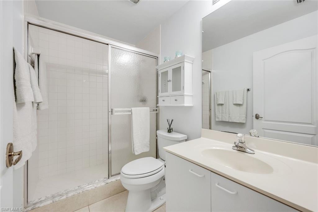 Full bath with a shower stall, vanity, and light tile patterned flooring