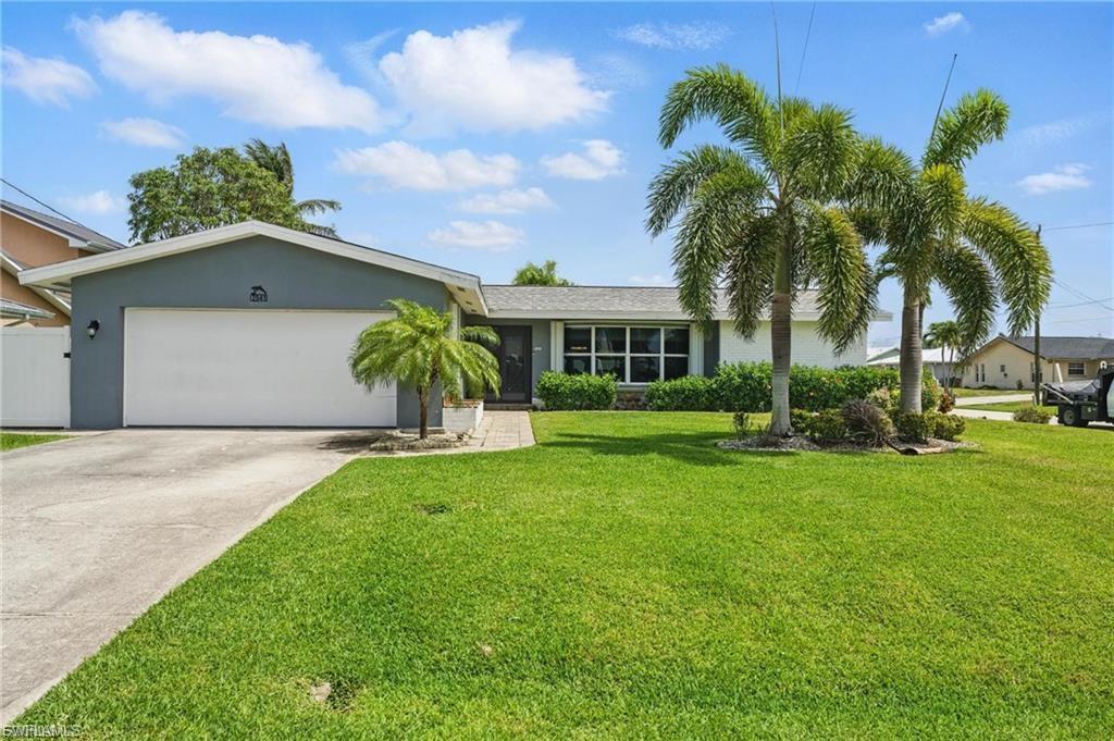 Single story home featuring a garage, driveway, a front yard, and stucco siding
