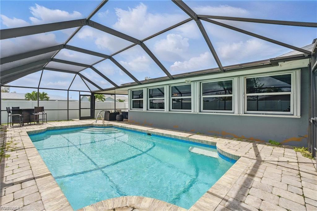 View of swimming pool featuring a sunroom, a patio, and glass enclosure