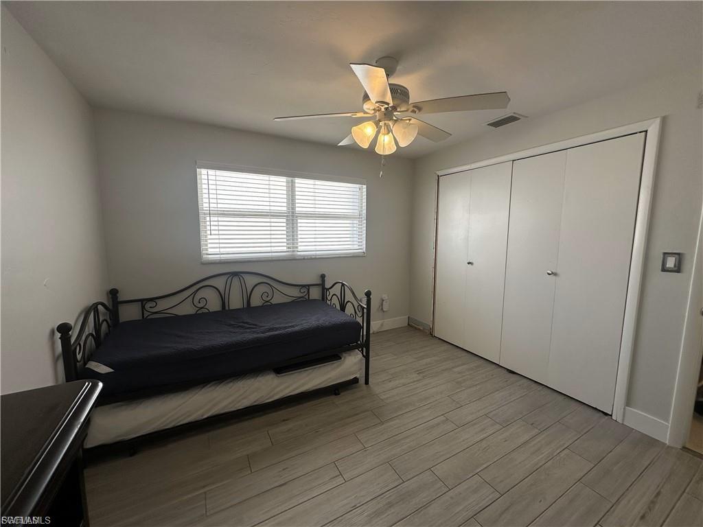 Bedroom with light wood-style flooring, ceiling fan, and a closet