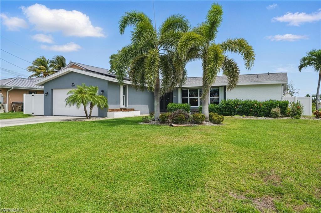 Ranch-style home with roof mounted solar panels, a garage, driveway, and stucco siding
