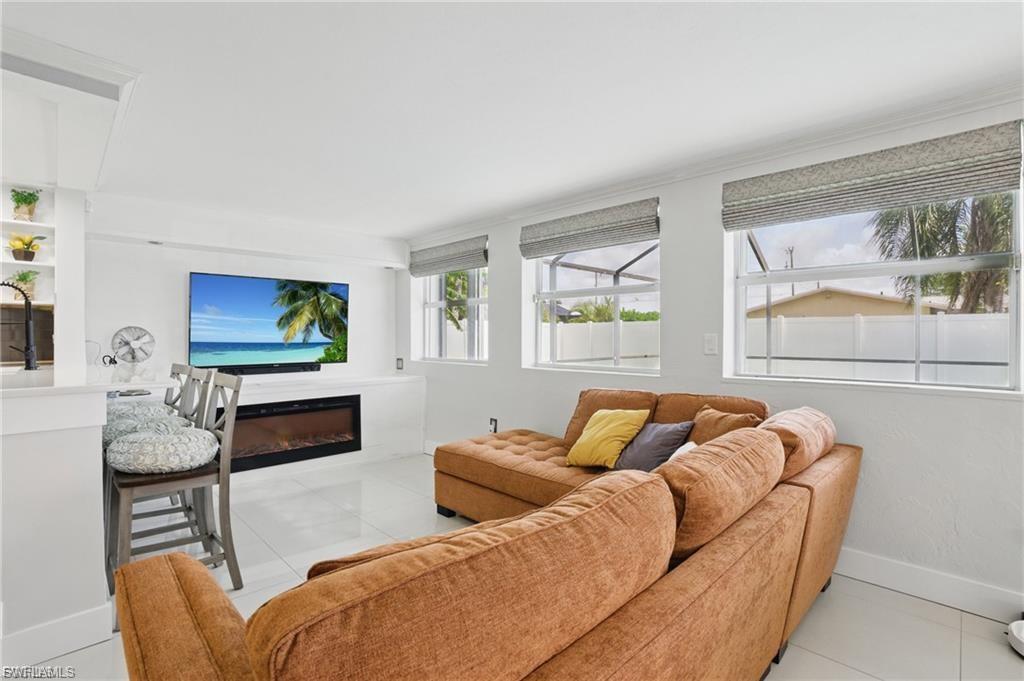 Living area featuring light tile patterned flooring and a glass covered fireplace