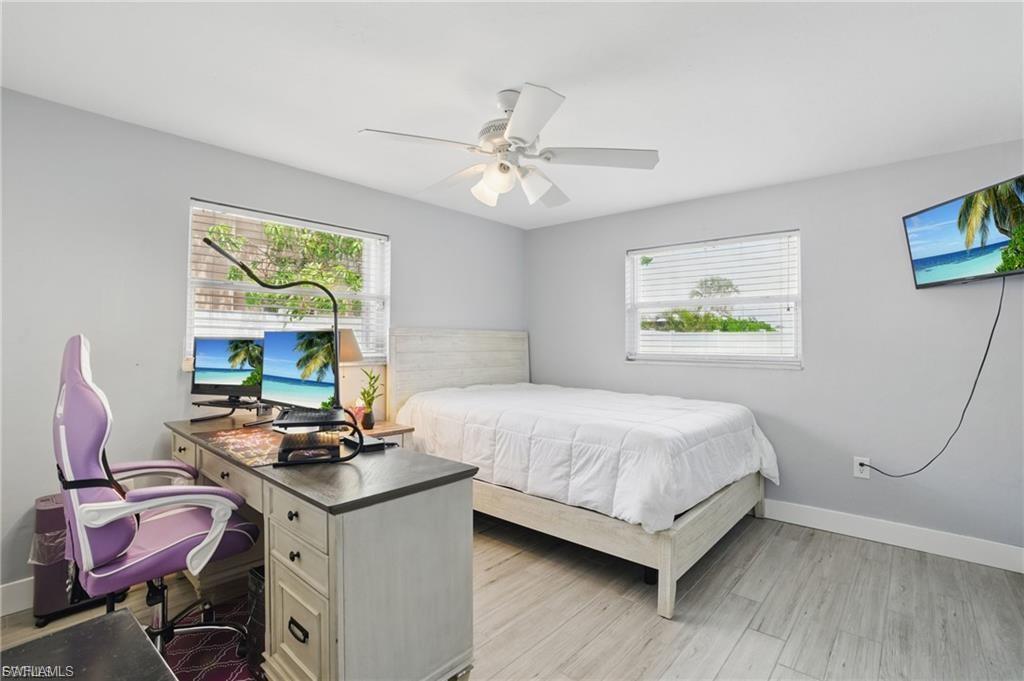 Bedroom with an office area, light wood-type flooring, and ceiling fan