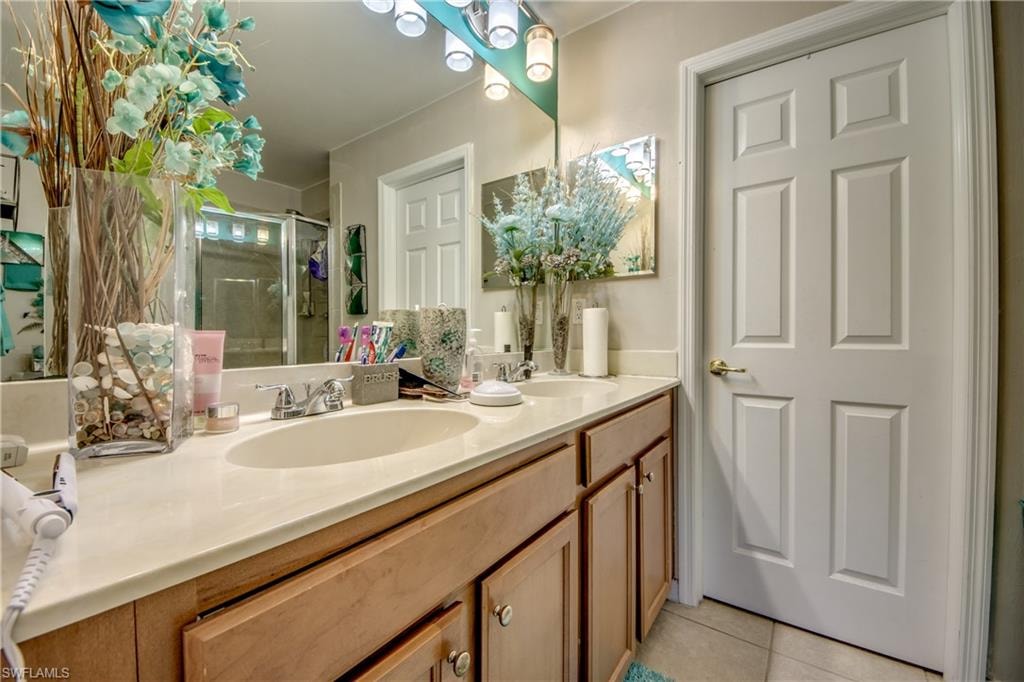Master bath with double vanity, light tile patterned floors, and a shower stall