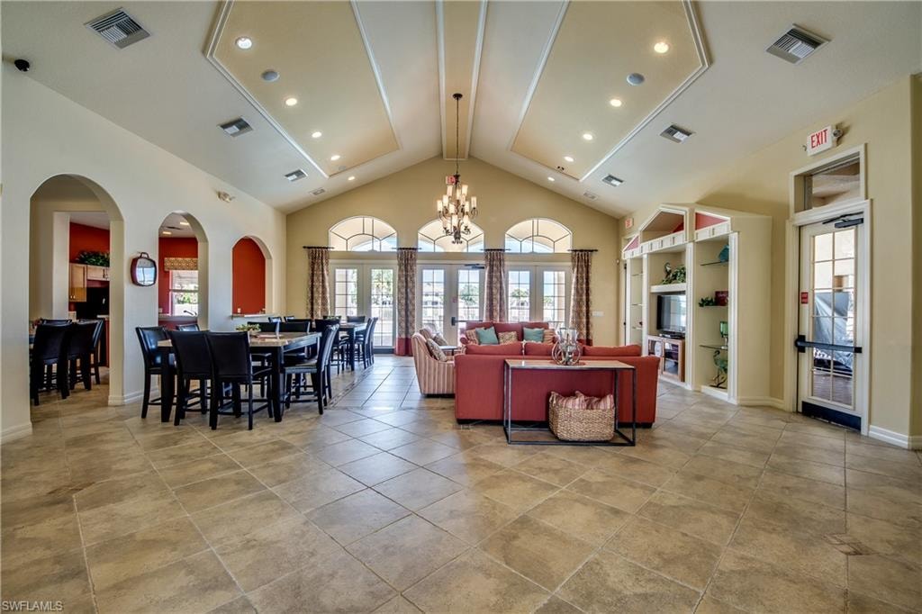 Another view of clubhouse with high vaulted ceiling, a chandelier, arched walkways, recessed lighting, and french doors