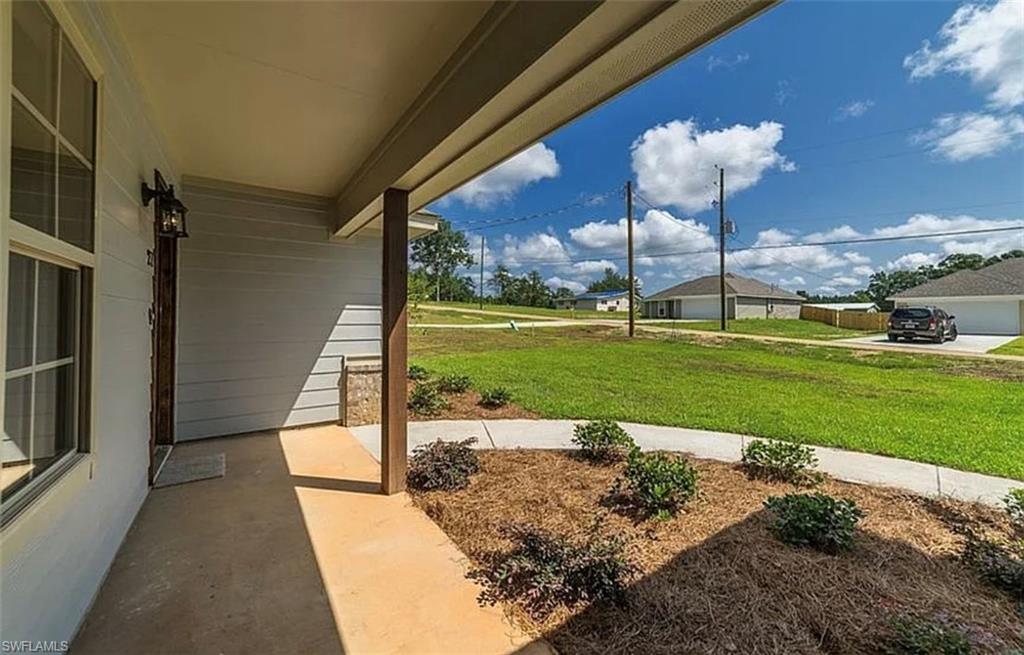 View of grassy yard featuring covered porch