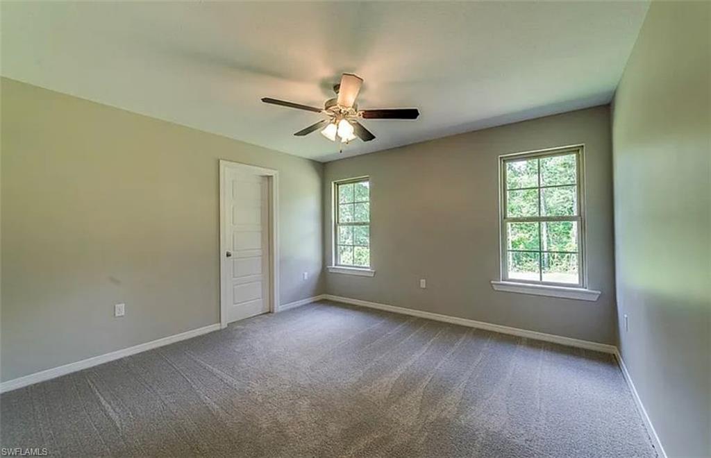 Unfurnished bedroom featuring carpet, multiple windows, and ceiling fan