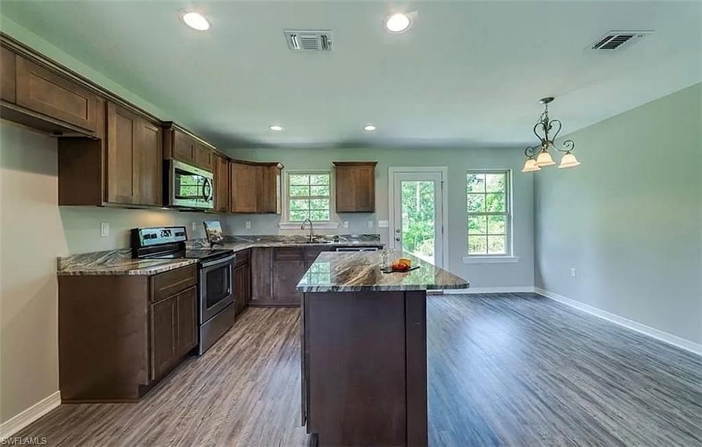 Kitchen featuring a center island, appliances with stainless steel finishes, recessed lighting, dark wood finished floors, and pendant lighting