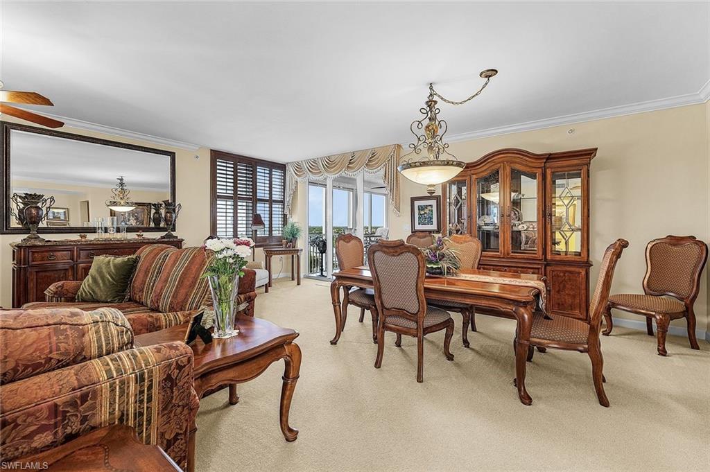 Dining area with ornamental molding, light colored carpet, and a ceiling fan