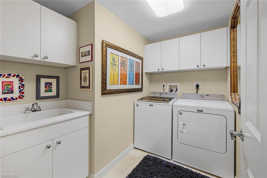 Laundry room with cabinet space, independent washer and dryer, and light tile patterned floors
