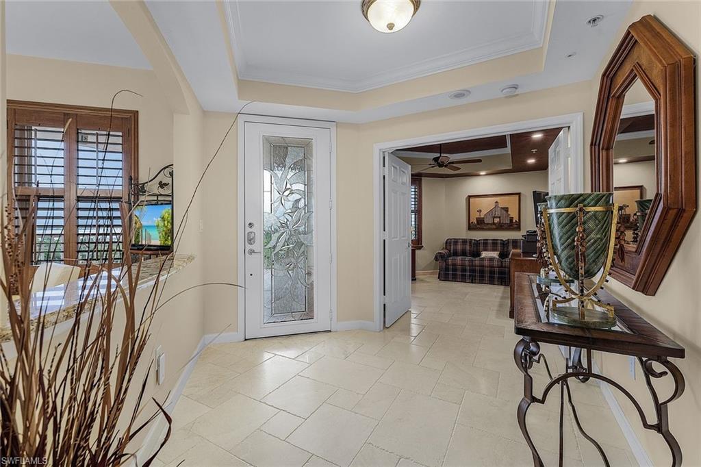 Foyer with a raised ceiling, crown molding, and ceiling fan