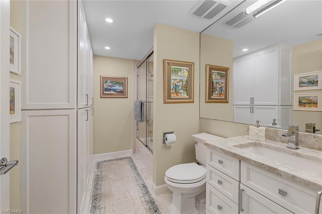 Full bath featuring vanity, enclosed tub / shower combo, recessed lighting, and light tile patterned flooring