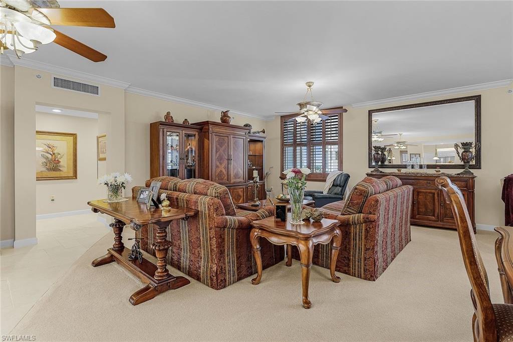 Living room featuring a ceiling fan, ornamental molding, and light colored carpet