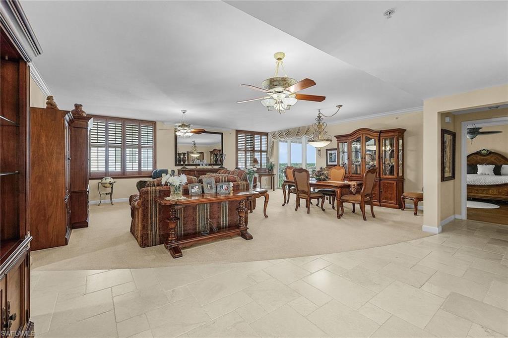 Living area featuring a ceiling fan, light colored carpet, and ornamental molding